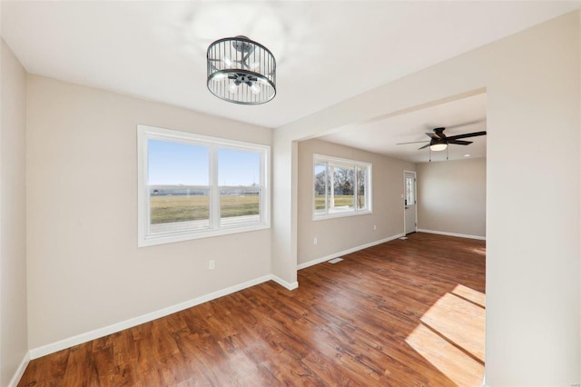 unfurnished room featuring a ceiling fan, wood finished floors, and baseboards