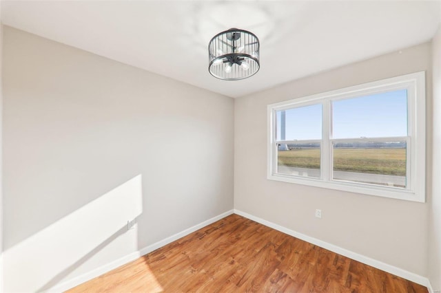 empty room with light wood-style floors, baseboards, and a chandelier