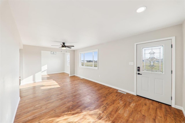 foyer with baseboards, wood finished floors, visible vents, and ceiling fan