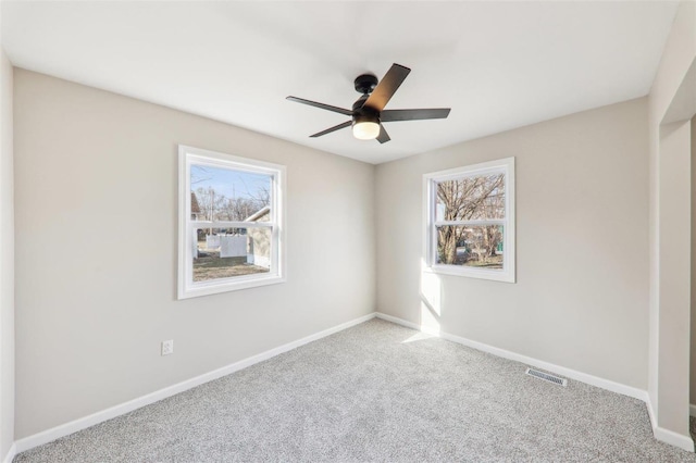 carpeted empty room with a ceiling fan, baseboards, and visible vents