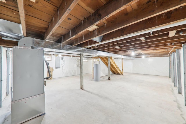 unfinished basement featuring gas water heater, stairway, and electric panel