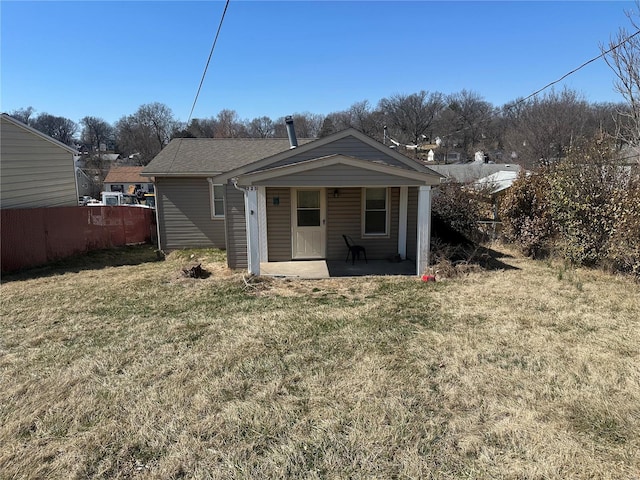 rear view of property featuring a yard and fence