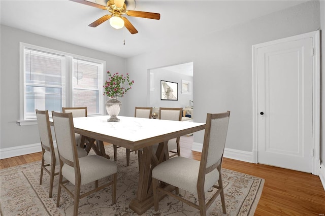 dining room with light wood-style flooring, a ceiling fan, and baseboards