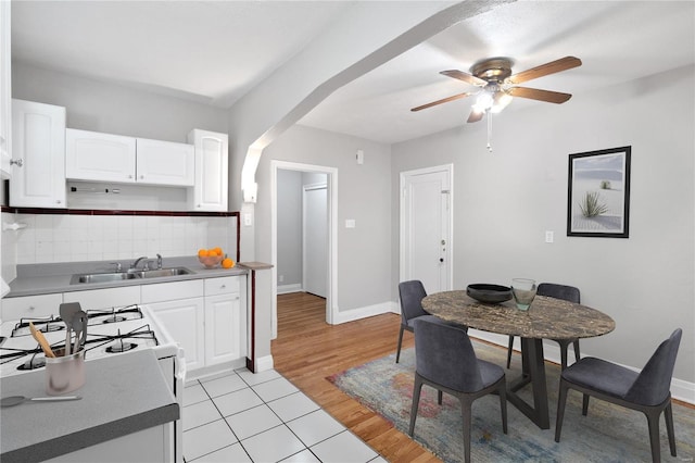 dining area featuring arched walkways, light wood-style flooring, baseboards, and ceiling fan