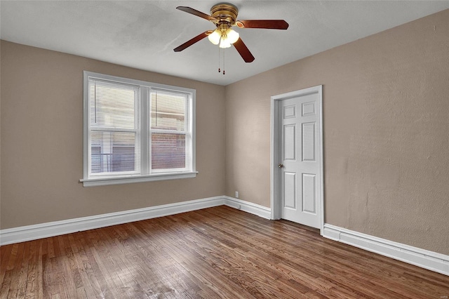 unfurnished room featuring ceiling fan, baseboards, and dark wood finished floors