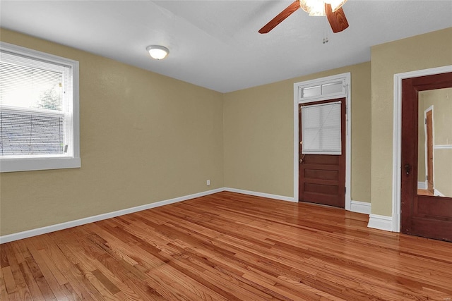 spare room with baseboards, light wood-type flooring, and ceiling fan