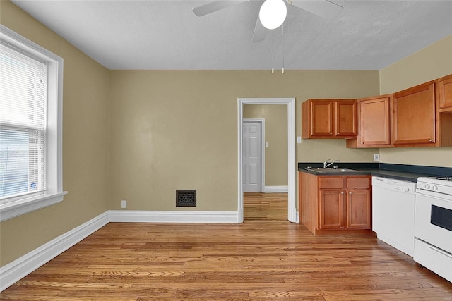 kitchen featuring white appliances, light wood-style flooring, plenty of natural light, and dark countertops