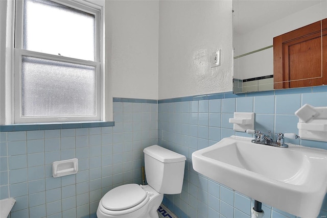 bathroom with toilet, tile walls, and a sink