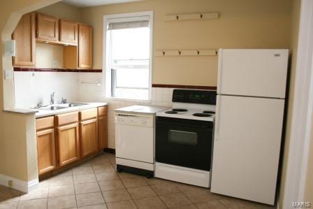 kitchen with tasteful backsplash, light countertops, light tile patterned floors, white appliances, and a sink