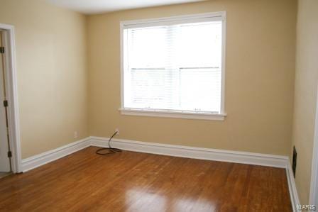 unfurnished room with baseboards, plenty of natural light, and wood finished floors