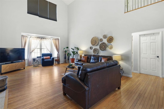 living room with baseboards, wood-type flooring, and a high ceiling