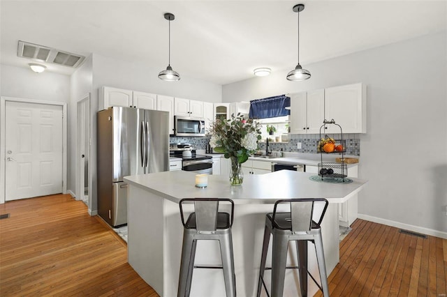 kitchen with visible vents, backsplash, white cabinetry, and stainless steel appliances