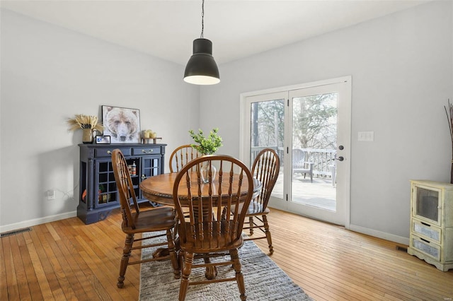 dining space featuring light wood-type flooring, visible vents, and baseboards