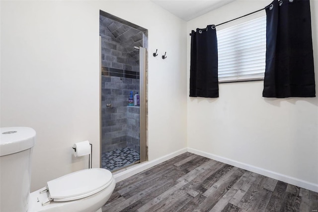 full bathroom featuring a stall shower, toilet, baseboards, and wood finished floors