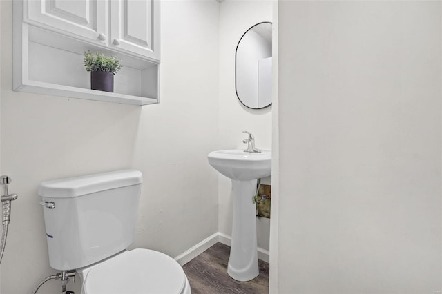 bathroom with toilet, baseboards, and wood finished floors