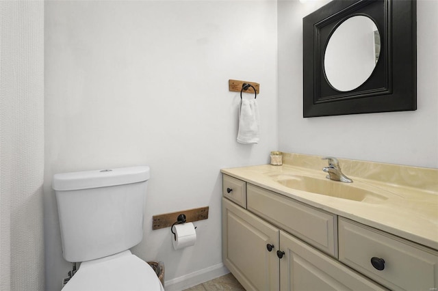 bathroom with baseboards, toilet, and vanity