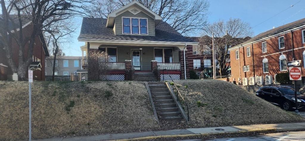 view of front facade with stairway, covered porch, and a shingled roof