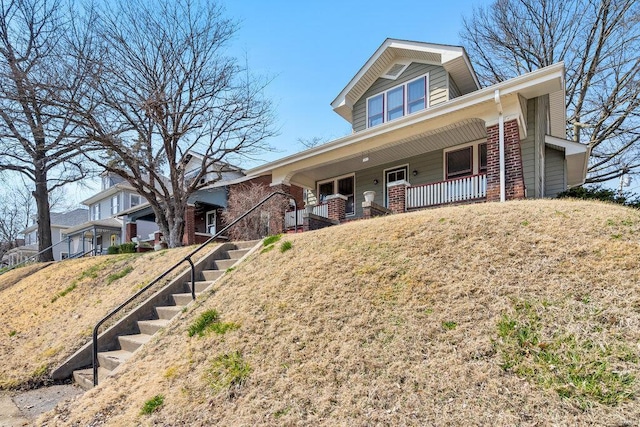 view of front of home with stairway, brick siding, and a porch