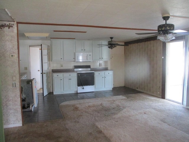 kitchen featuring white microwave, electric range, ceiling fan, white cabinets, and wood walls