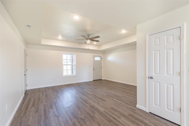 interior space featuring a raised ceiling, wood finished floors, baseboards, and visible vents