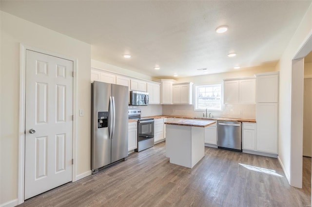 kitchen with light wood-style flooring, a sink, a center island, white cabinetry, and appliances with stainless steel finishes