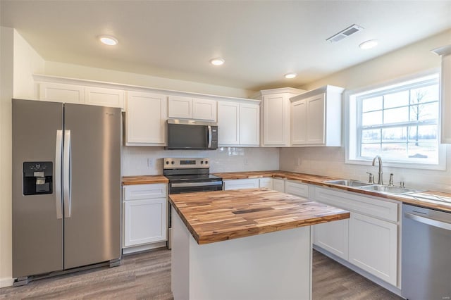 kitchen with visible vents, a sink, appliances with stainless steel finishes, white cabinets, and butcher block counters