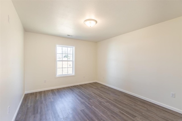 empty room with visible vents, baseboards, and dark wood-type flooring