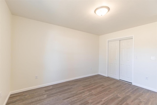 unfurnished bedroom with a closet, baseboards, and wood finished floors