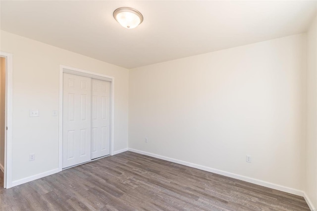 unfurnished bedroom featuring a closet, baseboards, and wood finished floors