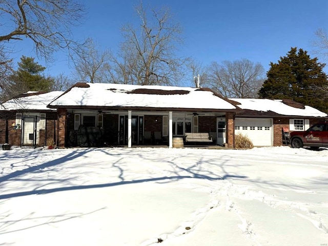 view of front of home featuring brick siding, covered porch, an attached garage, and a ceiling fan