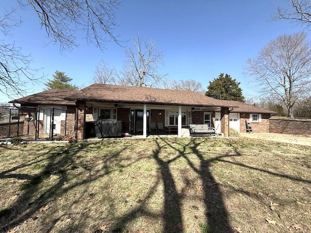 back of house with a yard, a ceiling fan, brick siding, an attached garage, and fence