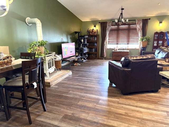 living room with a notable chandelier, wood finished floors, a wood stove, and vaulted ceiling