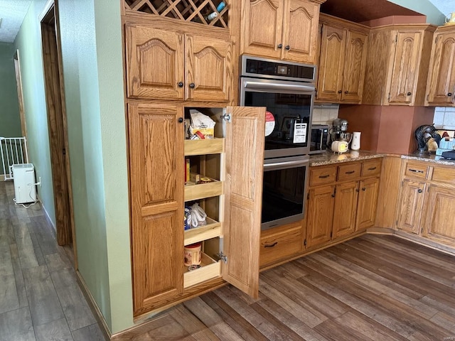 kitchen featuring dark wood-style floors, stainless steel appliances, and light stone countertops