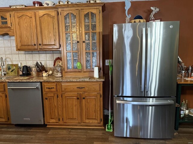 kitchen featuring decorative backsplash, dark wood-type flooring, appliances with stainless steel finishes, and brown cabinetry