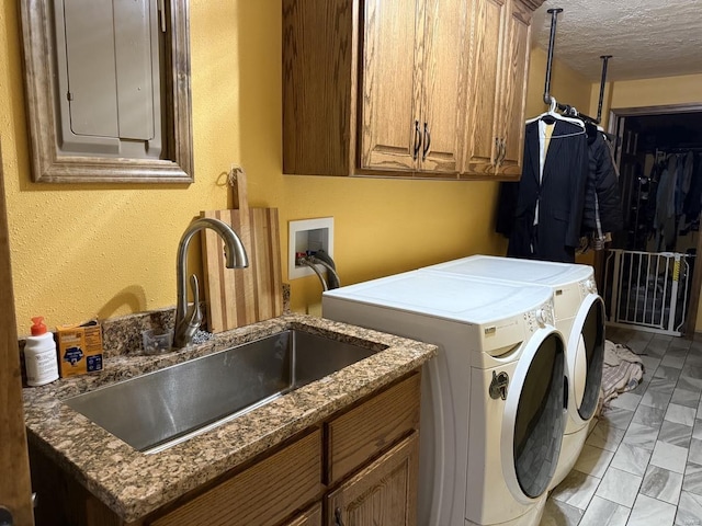 laundry area with cabinet space, washer and dryer, a textured ceiling, and a sink