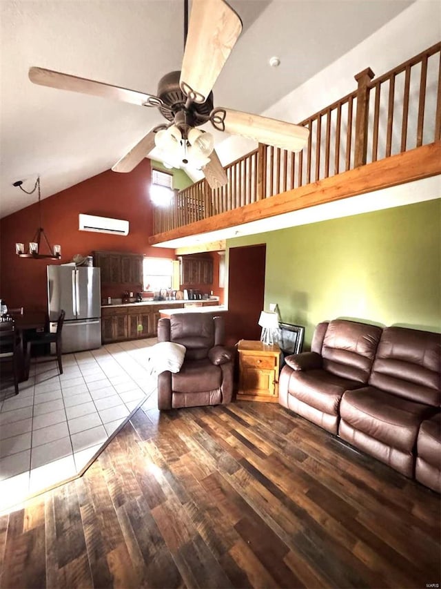 living room featuring a ceiling fan, a wall unit AC, wood finished floors, and high vaulted ceiling