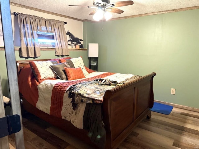 bedroom featuring wood finished floors, ornamental molding, ceiling fan, baseboards, and a textured ceiling