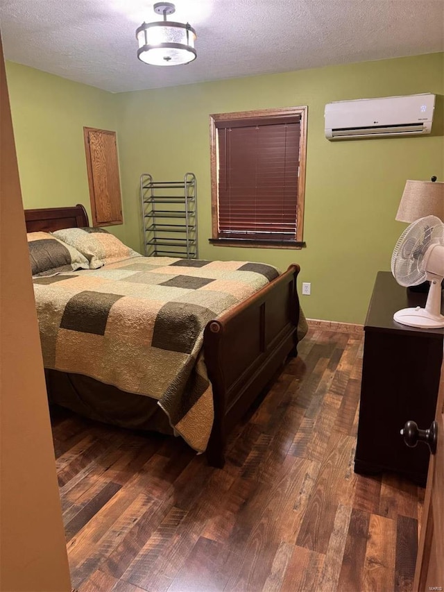bedroom with a textured ceiling, wood finished floors, and a wall mounted air conditioner