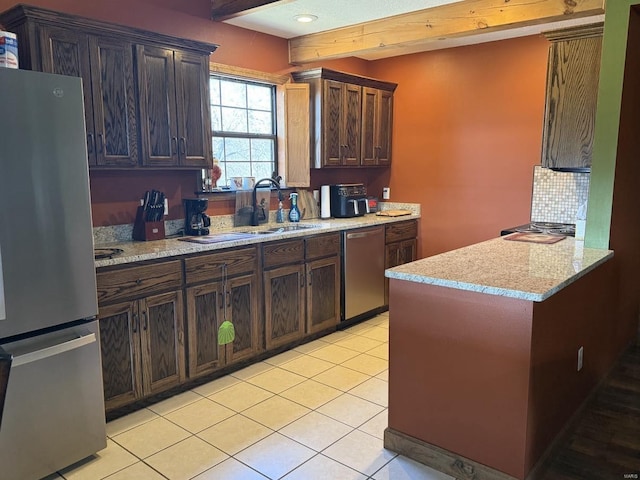 kitchen with a sink, light tile patterned floors, tasteful backsplash, light stone counters, and appliances with stainless steel finishes
