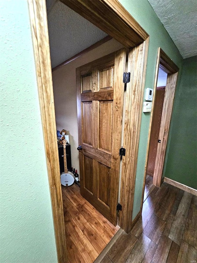 room details with a textured ceiling, wood finished floors, and baseboards