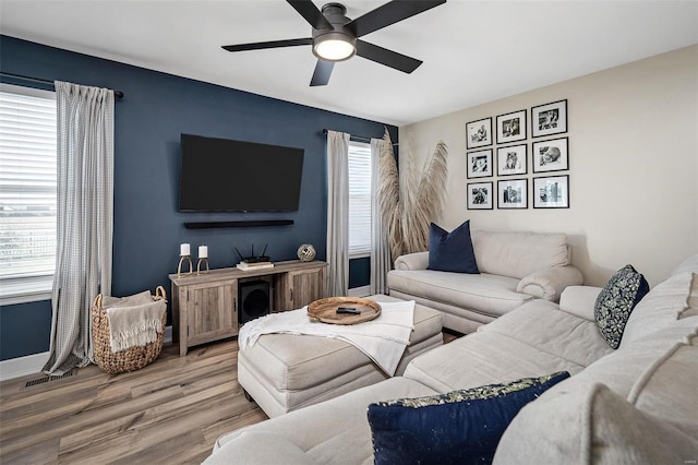 living area with visible vents, baseboards, ceiling fan, and wood finished floors