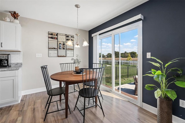 dining room with light wood-style flooring, a notable chandelier, and baseboards