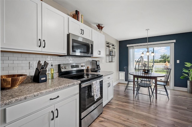 kitchen featuring backsplash, white cabinets, stainless steel appliances, and light wood-type flooring