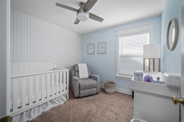 carpeted bedroom featuring ceiling fan, a crib, and baseboards