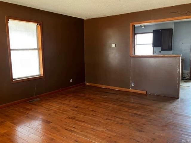 empty room featuring wood finished floors, baseboards, and a textured ceiling