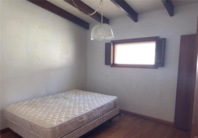 bedroom featuring beamed ceiling, baseboards, and wood finished floors