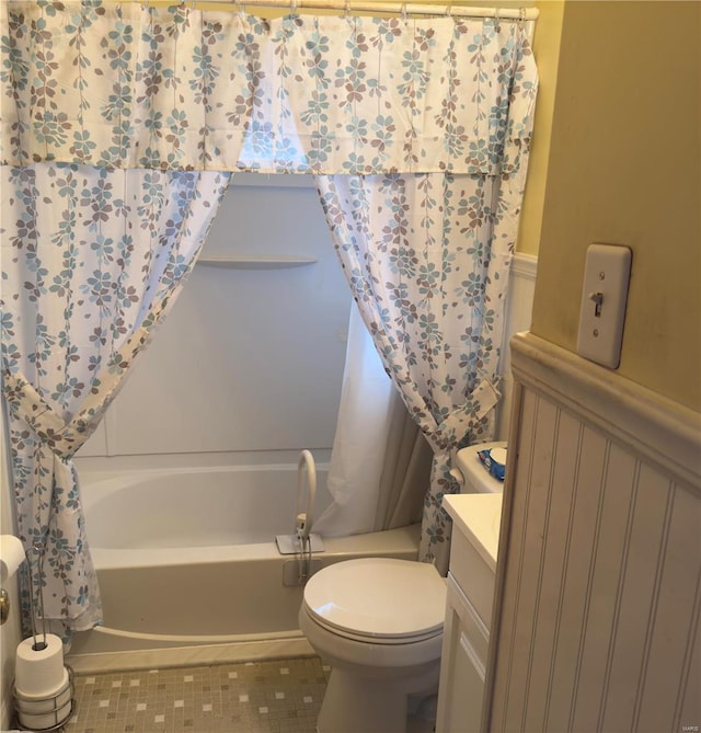 bathroom featuring a wainscoted wall, toilet, shower / tub combo, tile patterned floors, and vanity