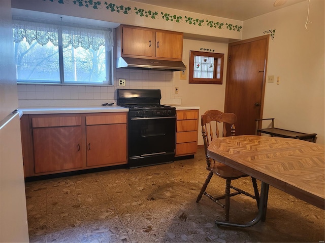 kitchen featuring black gas range oven, decorative backsplash, light countertops, under cabinet range hood, and dark floors