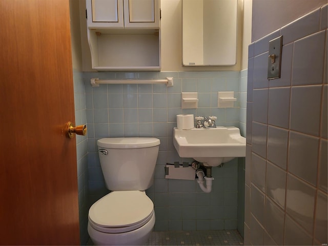 bathroom with a sink, toilet, and tile walls