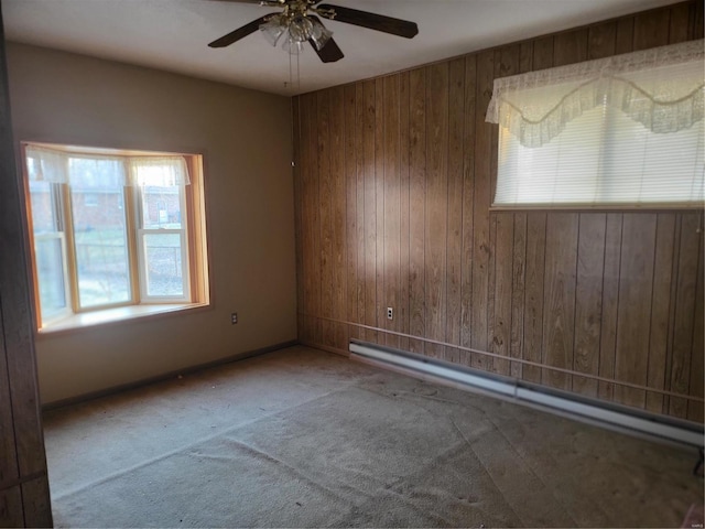 unfurnished room featuring wood walls, a baseboard radiator, ceiling fan, and carpet floors